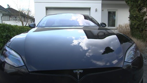 Ein schwarzes Tesla E-Auto vor einer Garage