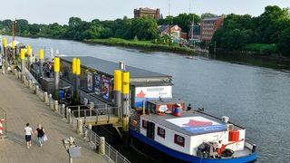 Ein Schiff liegt an einem Flussufer.