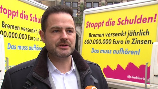 Thore Schäck vor zwei Plakaten