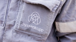 Thyssenkrupp-Logo auf der Jackentasche eines Arbeitsanzugs (Archivbild)