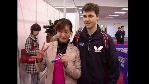 Tischtennisspieler Timo Boll steht für ein Foto lächelnd neben einer Chinesin am Rande eines Turniers.