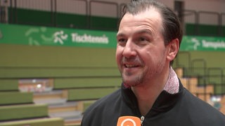 Tischtennis-Profi Timo Boll steht lächelnd nach dem Sieg gegen Werder Bremen in der leeren Halle beim Interview.