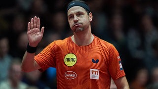 Tischtennis-Legende Timo Boll verabschiedet sich fast entschuldigend beim Bremer Publikum mit erhobener Hand und aufgeblasenen Backen.