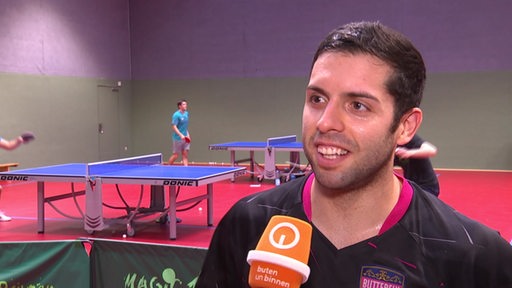 Werders Tischtennis-Profi Marcelo Aguirre steht lächelnd in der Trainingshalle bei einem Interview.