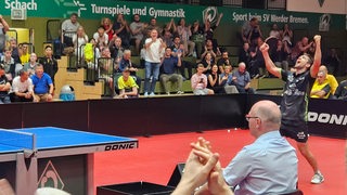 Werders Tischtennis-Profi Kirill Gerassimenko reißt nach seinem Sieg im Heimspiel gegen Dortmund die Arme hoch und jubelt.