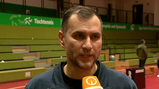 Werders Tischtennis-Trainer Cristian Tamas steht nach einem Spiel in der leeren Sporthalle beim Interview.