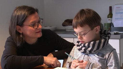 Ein Kind mit seiner Mutter bei den Hausaufgaben.