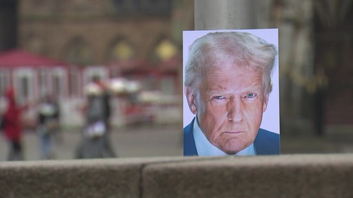 Ein Bild von Donald Trump auf einer Mauer in der Stadt.