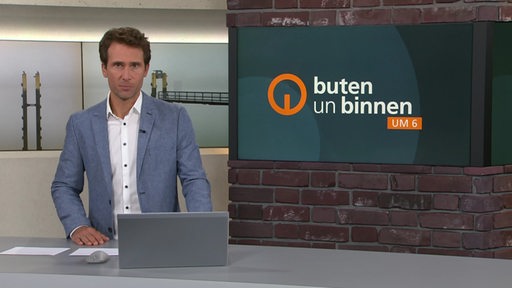 Der Moderator János Kereszti steht im Studio von buten un binnen hinter einem Pult.