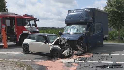 Ein Mini und ein Kleinlaster stehen nach einem Unfall schwer beschädigt auf einer Straße