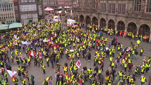 Demonstrierende Menschen in gelben Warnwesten und mit Ver.di-Flaggen  auf dem Bremer Marktplatz. 