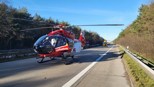 Auf einer Autobahn stehen zwei Hubschrauber.