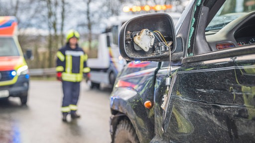 Ein Auto steht auf einer Straße, Fenster und Seitenspiegel sind zertrümmert