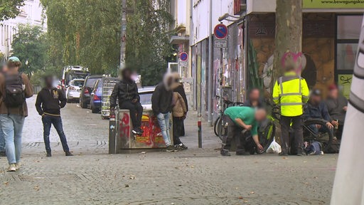 Zu sehen sind mehrere junge Männer, welche sich im Viertel aufhalten.