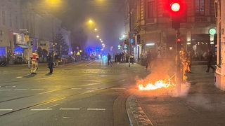 Eine Straße, der rechte Bürgersteig brennt.