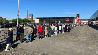 Eine Menschenschlange vor der Messehalle 7