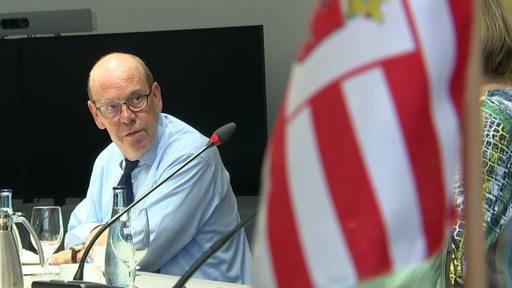 Der Landeswahlleiter Andreas Cors bei der Pressekonferenz, im Vordergrund die Bremer Flagge. 