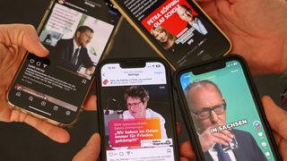 Mehrere Menschen schauen sich Auftritte von Landespolitikern in sozialen Netzwerken auf ihren Mobiltelefonen an.