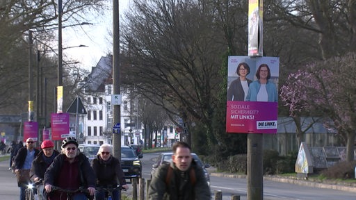 Wahlplakate hängen an Straßenbeleuchtung am Deich.