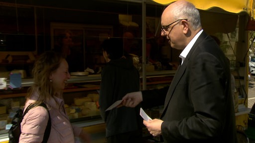 Der Bremer Bürgermeister Andreas Bovenschulte gibt einer Passantin seinen Flyer für die Wahlen. 