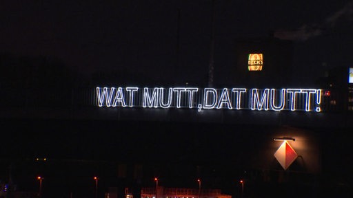 Leuchende Schrift "Wat mutt dat mutt" auf der Brücke