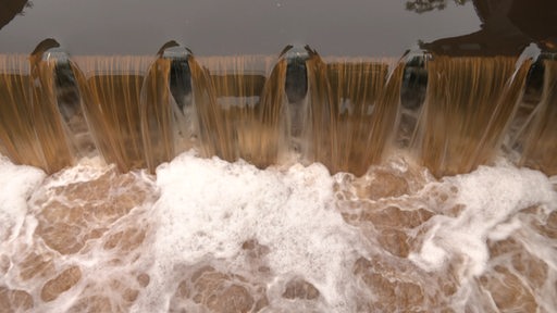 Wasser fließt durch ein Wehr in der Wümme.