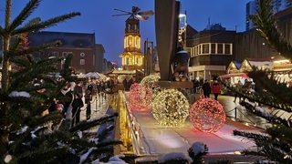 Auf einem Weihnachtsmarkt leuchten Lichter.