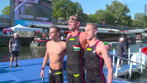 Der Schwimmer Florian Wellbrock und zwei weitere Schwimmer posen für ein Bild bei der Olympia.