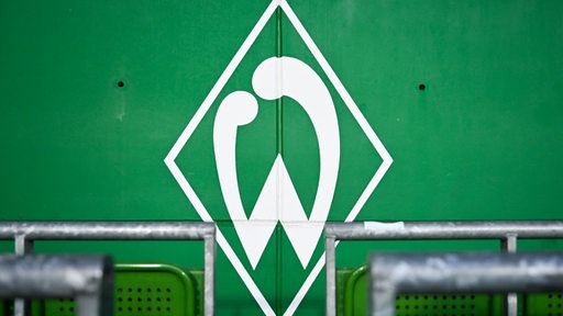 Das Werder-W ist an einer Wand hinter grünen Sitzen zu sehen