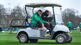 Marco Friedl sitzt auf einem Golfcart und hält sich den rechten Fuß.