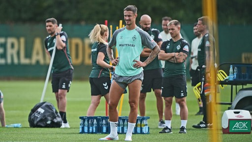 Marco Friedl hat seine kurze Hose weit hochgezogen. Seine Hände hat er in den Hüften.