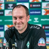 Werder-Trainer Ole Werner lächelt während einer Pressekonferenz.