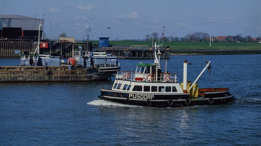 Ein kleines Schiff fährt einen Fluss entlang.