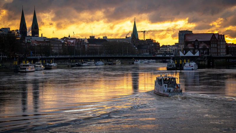 Ein Schiff fährt im Sonnenaufgang auf der Weser. 