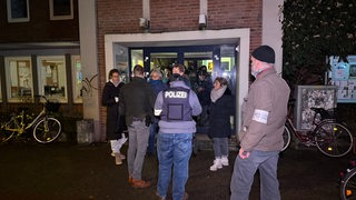 Um den Eingang der Gemeinde stehen Polizei und andere.